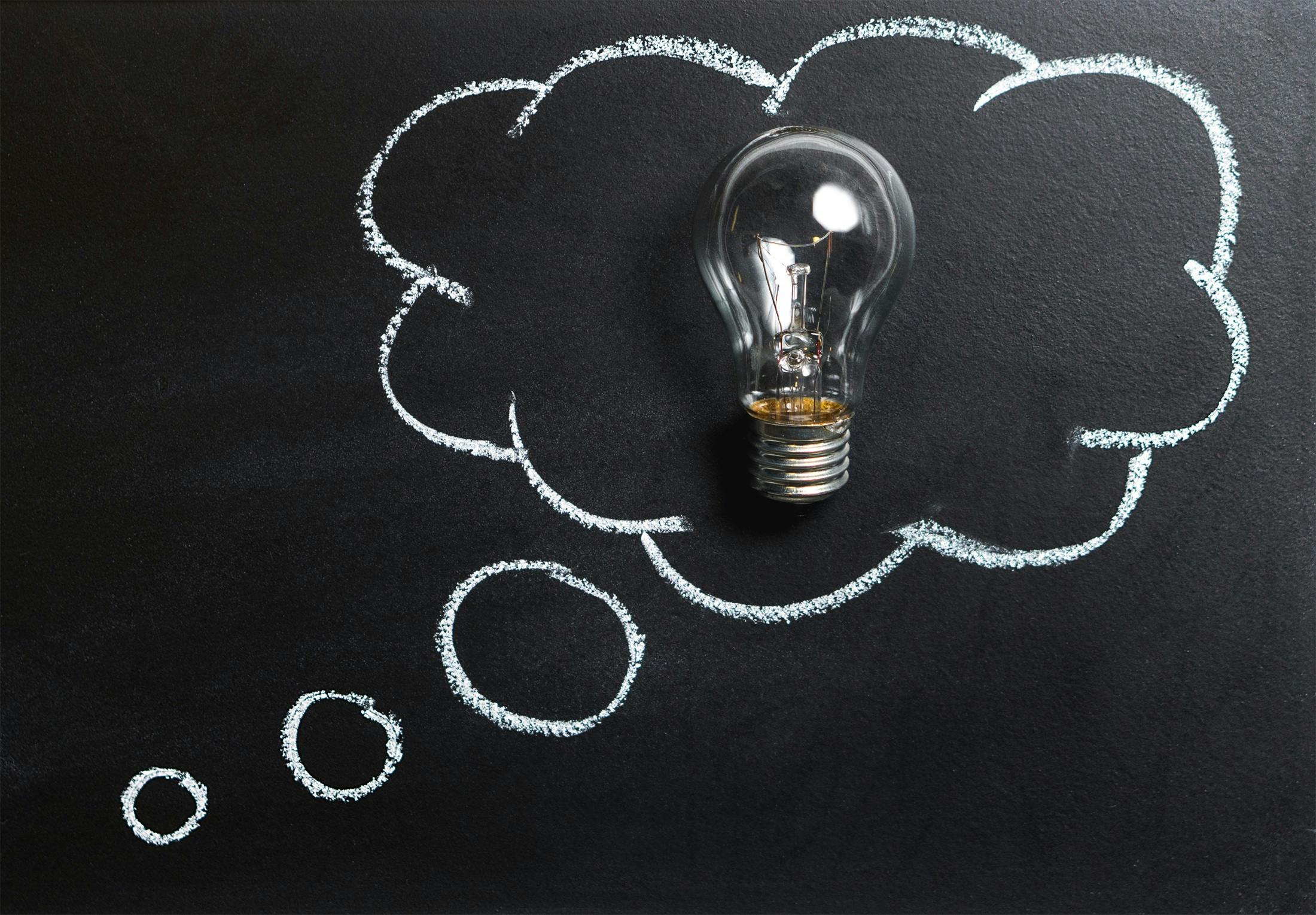 lightbulb in a speech bubble drawn in chalk on a blackboard